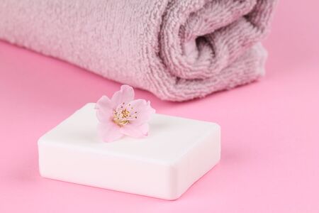 A towel and peach soap on a pink background. Bodycare.