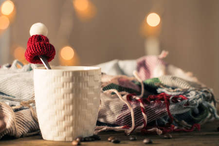 A cup of coffee, a scarf and a small hat in blurredの写真素材