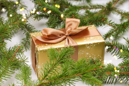 Golden gift box with a cute bow and fir branches. Christmas.