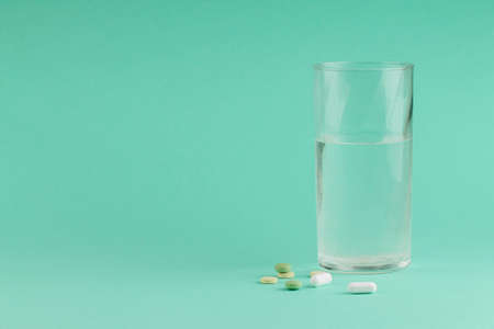 Pills with a glass of water on greenの写真素材