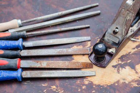 Selection of old used chisels and a plane tool on a dark wooden table