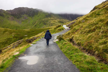 Person walking on a path in Snowdonia National Park, North Wales, United Kingdom; view of the mountains, selective focusの写真素材