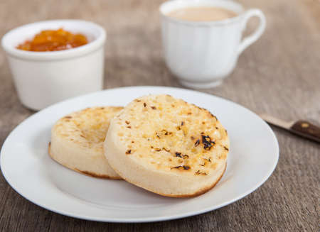Hot toasted crumpets on the wooden table with blueberries and jam on the backの写真素材