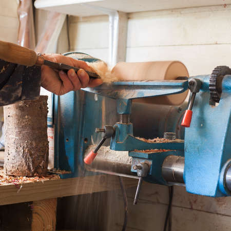 Man using old wood lathe turning wood, selective focus, dark toned photoの写真素材