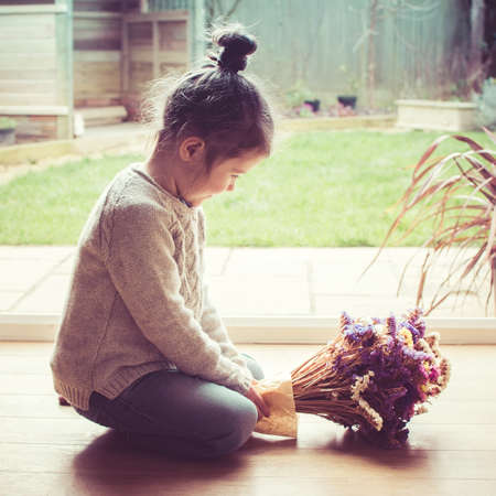 Little toddler girl sitting on the floor holding staticesの写真素材