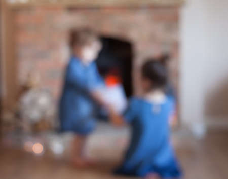Abstract blurred background of two little girls in front of the fireplaceの写真素材