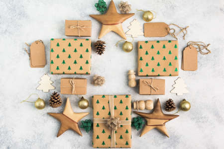 Brown Christsmas present boxes with sparkling embossed fir trees, pine cones, golden baubles, wooden decorations, jute twine arranged in a frame, top view, copy space for textの写真素材