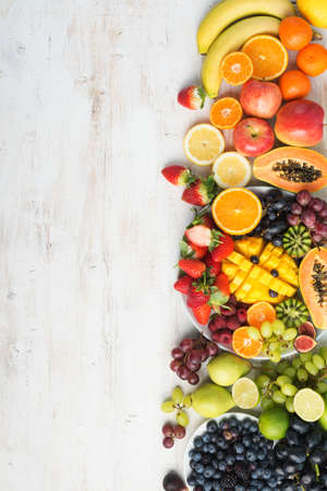 Assortment of fresh fruits and vegetables in rainbow colours on the off white table verical, top view, selective focusの写真素材
