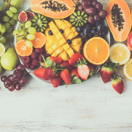 Fresh fruits and vegetables in rainbow colours on the off white table, copy space, square, toned, selective focusの写真素材