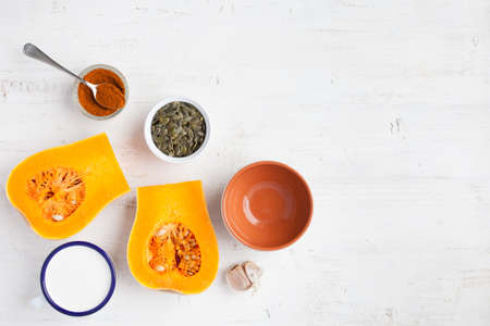 Spicy butternut squash soup ingredients on the white wooden table with copy space for text, top view