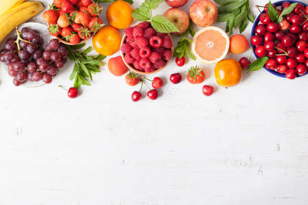 Summer fruits and berries strawberries, cherries, raspberries, oranges, grapes, persimmon on a white table, space for text, selective focusの写真素材