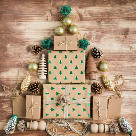 Top view of brown Christmas present boxes in arrangement, with sparkling embossed fur trees, pine cones, golden baubles, wooden decorations, jute twine, copy space for textの写真素材