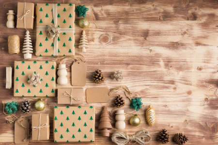 Above view of brown Christmas present boxes in arrangement, with sparkling embossed fur trees, pine cones, golden baubles, wooden decorations, jute twine, copy space for textの写真素材