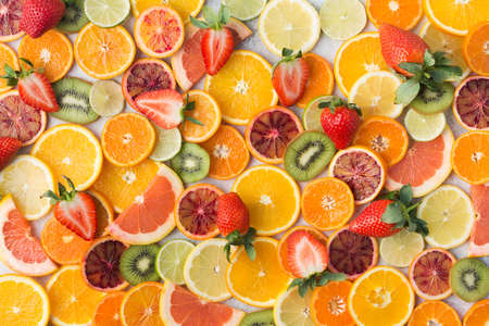 Colourful fruit pattern, oranges, clementines, blood oranges, kiwis, strawberries and grapefruits on white table background, top view, selective focusの写真素材