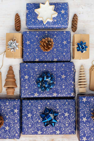 Presents in dark blue wrapping paper with silver stars and sparkles and wooden decorationsの写真素材