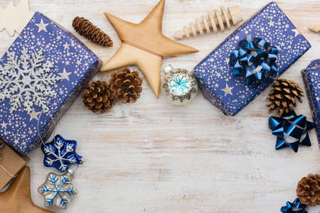 Chritmas background. Presents in blue wrapping paper with silver sparkles, wooden decorations, ornaments on white table, selective focusの写真素材