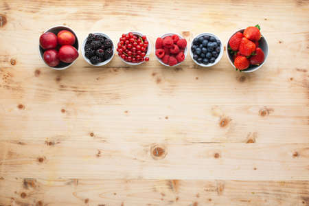 Top view of mixed berries in bowls, strawberries blackberries blueberries plums red currants raspberries, copy space, selective focusの写真素材