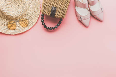 Summer fashion background on pink, trendy straw bag, fedora hat, heeled shoes and yellow sunglasses,...