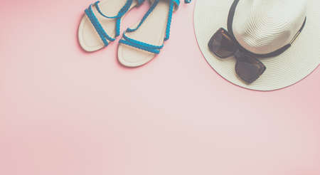 Straw hat, sunglasses and blue shoes on pink background, beach holiday concept. Top view, toned, selective focusの写真素材