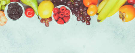 Healthy fruits berries background, strawberries raspberries oranges plums apples kiwis grapes blueberries mango on the white, top view, copy space for text, selective focus. Long photo banner, tonedの写真素材