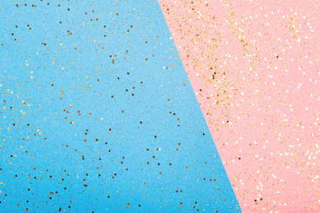 Golden glitter scattered on the pink blue card background, top view, selective focus
