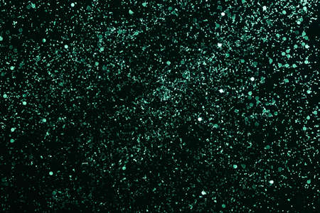 Turquoise green glitter scattered on the black card background, top view, selective focusの写真素材