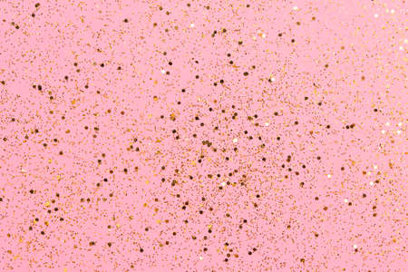 Golden glitter scattered on the pink card background, top view, selective focus