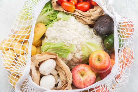 Zero waste eco friendly shopping concept, vegetables fruits in white mesh cotton and paper bags on...