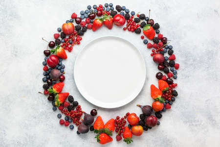 Colorful berries background frame. Strawberries blueberries red currant blackberries raspberries, top view on white table, copy space for text, selective focusの写真素材
