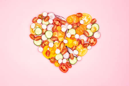 Heart made of bright colorful vegetables with copy space. Salad ingredients, tomatoes cucumber...