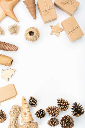 Christmas frame background in the shades of brown on white. Top view of gift boxes, various accessories, wooden decorations, pinecones, tags, copy space, selective focusの写真素材