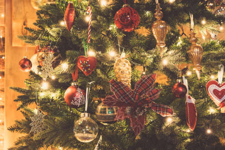 Close up of decorated Christmas tree, poinsettia flower, baubles, fairy lights, toned, selective focusの写真素材