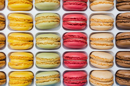 Classical french dessert. Colorful macarons in bright pink green yellow cream chocolate stacked in a...