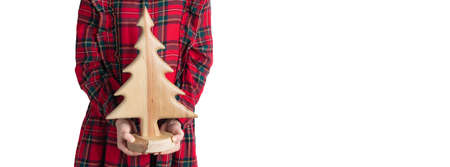Little girls hands holding handmade wooden Christmas tree. Child in red tartan dress, white background, selective focusの写真素材