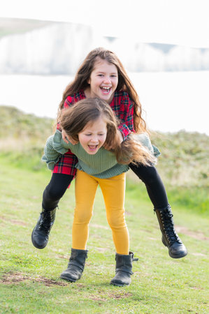 Two little girls sisters playing outdoor near Cuckmere beach located between Eastbourne and Seaford, East Sussex, British south coast, selective focusの写真素材