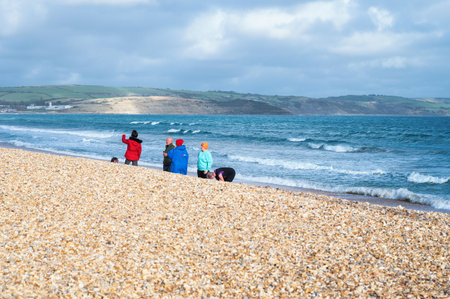 Weymouth, United Kingdom - October 30 2022: People on the pebble and sandy beach in Dorset, South West, United Kingdom, selective focusのeditorial素材