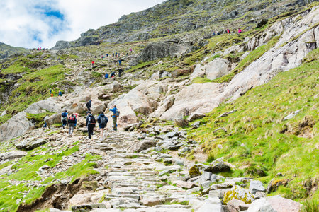 Snowdonia, Wales, United Kingdom May 28, 2019: People Climbing up the mount Snowdon in North Wales, view of the stone path, mountains, green grassのeditorial素材