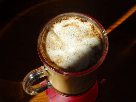 coffee with foam in a glass cup on a wooden floor