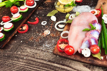 Raw fresh chicken gizzards and chicken with vegetables and herbs on a kitchen wooden tableの写真素材