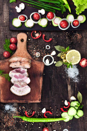 smoked pork bacon with vegetables and herbs on a kitchen wooden tableの写真素材