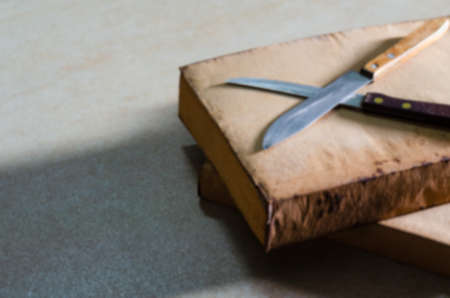 Blurred images of two old knives with handles made of hardwood material placed on an old book with a...
