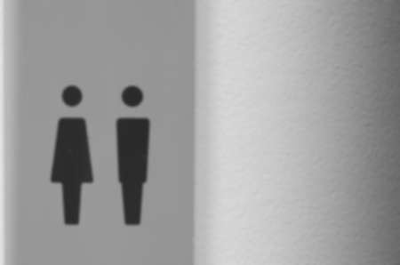 Blurred images of signposts to the toilets of ladies and gentlemen and mounted on concrete walls.