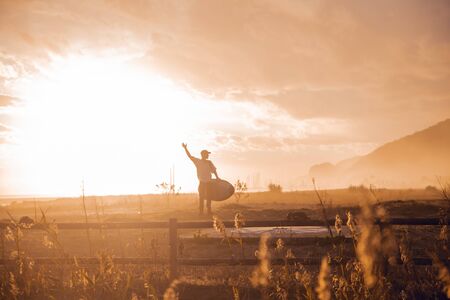 Sunset portrait of surfer boy with cap and surfboard in Barcelonaの写真素材
