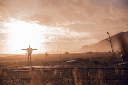 Sunset portrait of surfer boy wearing cap and walking on the beachの写真素材