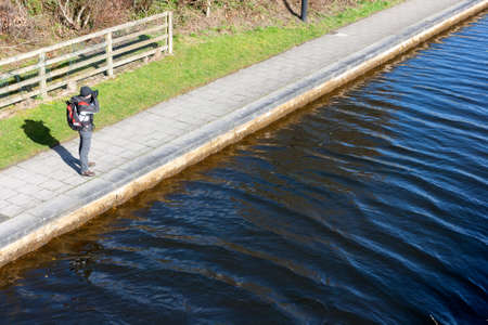 young man photographing on the riverbank の写真素材