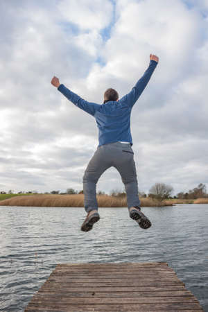 Young adult jumping on the edge of a dockの写真素材