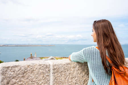 Rear view traveling woman looking at coastの写真素材