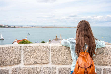 Rear view traveling woman looking at coast