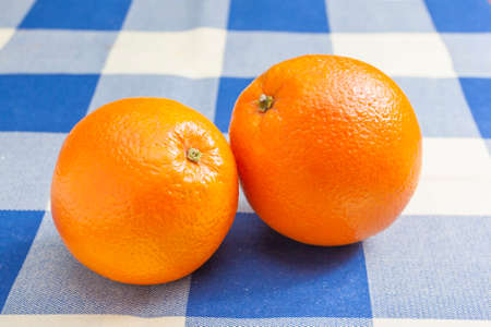 Close-up of two oranges on blue and white table cloth