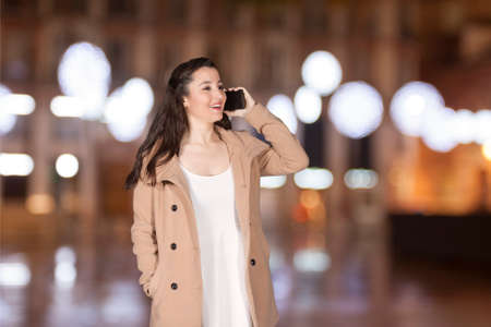 Beautiful woman talking by phone with a christmas backgroundの写真素材